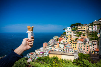 Close-up of hand holding cone against townscape