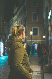 Side view of woman standing on street at night