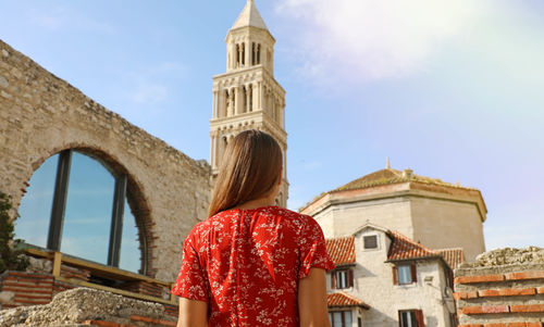 Rear view of woman standing against buildings and sky