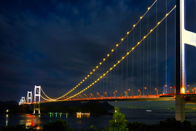 Illuminated suspension bridge over river at night