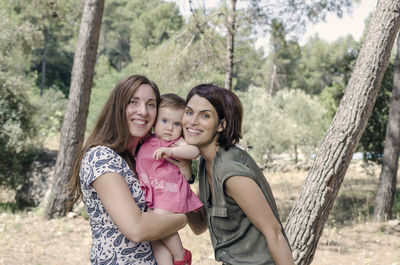 Portrait of mother and daughter on tree trunk