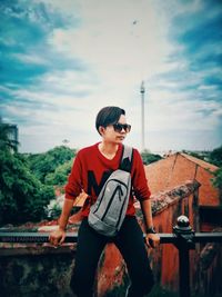 Young man wearing sunglasses standing against sky