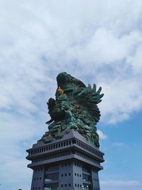 Low angle view of statue of building against cloudy sky