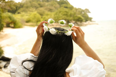 Rear view of woman holding white flowering plants