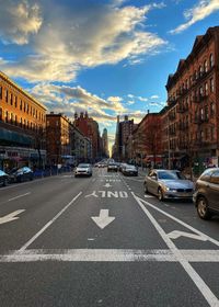 Cars on road by buildings against sky in city