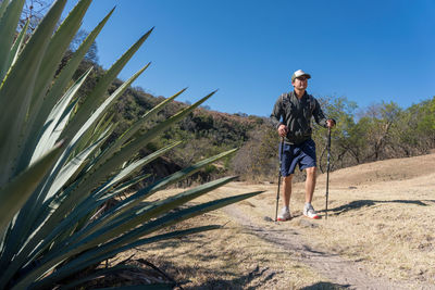 Full length of man walking on field against clear blue sky