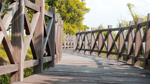 Wooden footbridge on footpath against sky