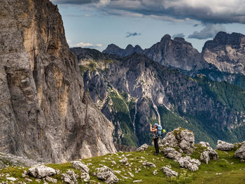 Full length of woman standing on cliff against mountains