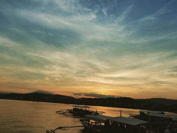 Silhouette boats in sea against sky during sunset