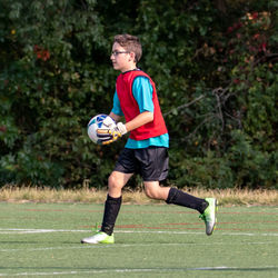 Full length of a boy playing soccer on grass