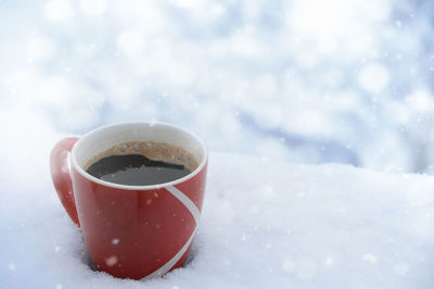 Close-up of coffee cup in snow