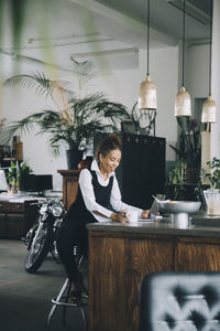 Smiling businesswoman sitting at kitchen island in creative office