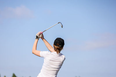 Rear view of woman with umbrella against sky