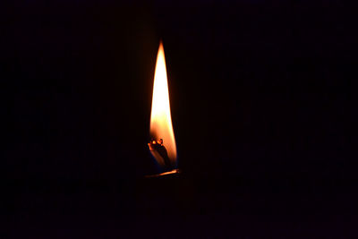 Close-up of lit candle in darkroom