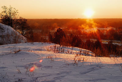 Scenic view of snowy landscape against clear sky during sunset