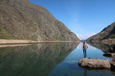 Rear view of woman standing by lake against sky