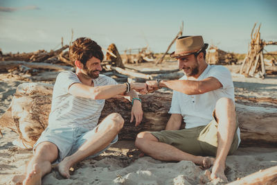 Men sitting on beach against sky