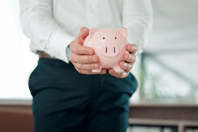 Midsection of man holding piggy bank