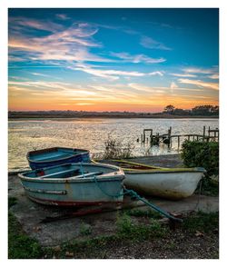 Boat moored on shore against sky during sunset