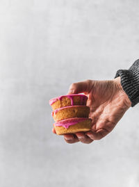 Close-up of hand holding ice cream against white background