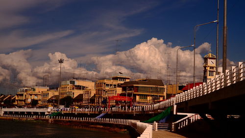 Bridge over river amidst buildings in city against sky