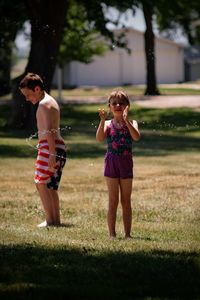 Full length of girl and woman standing on grass