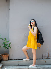 Young woman looking away while standing against wall