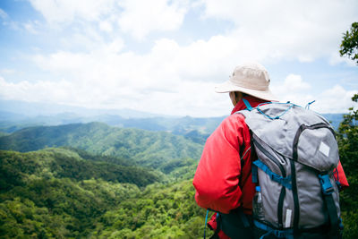 Rear view of man standing on mountain against sky