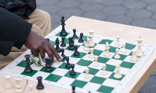 Midsection of person holding paper currency on chessboard