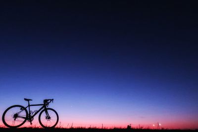 Silhouette bicycle against clear sky at night