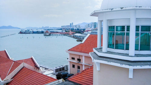 Houses by sea against sky in city