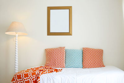 Low angle view of electric lamp on bed against wall at home