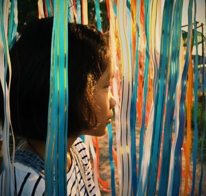 Side view of thoughtful girl looking away while standing by ribbons