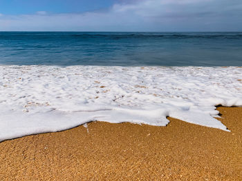 Low angle shot of an ocean wave washing up onto sandy shore