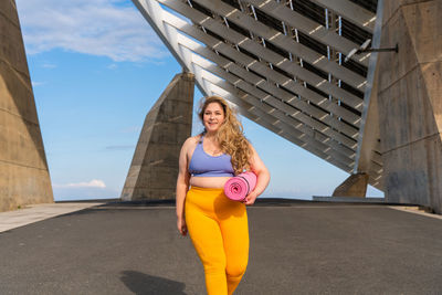 Portrait of young woman walking against building