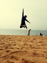 People jumping on beach against sky