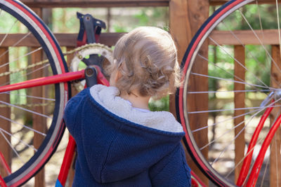 Rear view of boy playing with bicycle