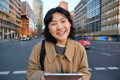 Portrait of young woman using mobile phone in city