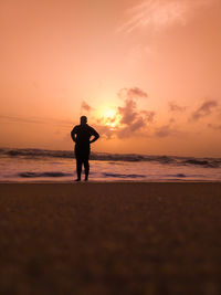 Silhouette man standing on beach against sky during sunset