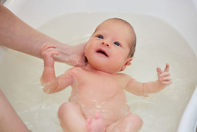 Cropped hands of mother bathing baby