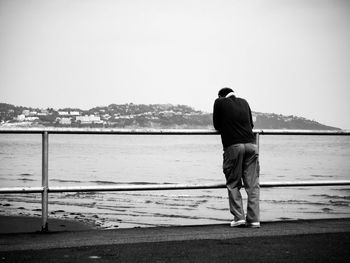 Rear view of man looking at sea against clear sky