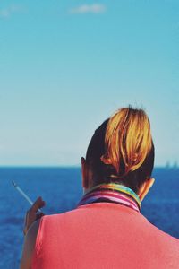 Rear view of woman looking at sea against clear sky