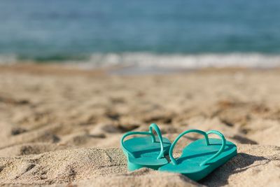 Green flip-flops on sandy beach