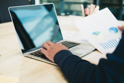 Midsection of man using laptop on table