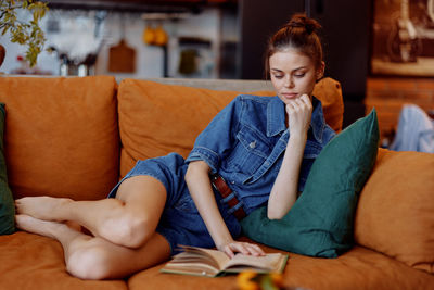 Young woman sitting on sofa at home