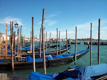 Boats moored in canal against blue sky