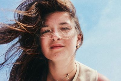 Close-up portrait of young woman against sky