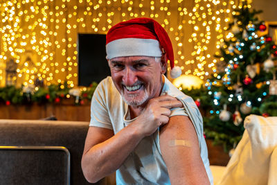 Portrait of a mature male smiling after getting a vaccine - man showing her arm with plaster