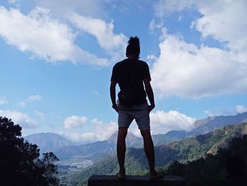 Rear view of man standing on mountain against sky