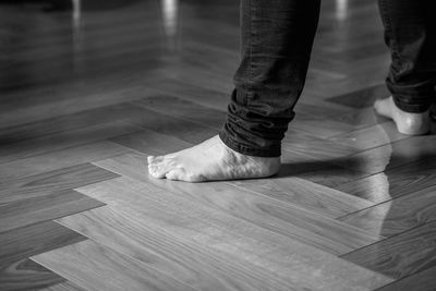 Low section of person standing on hardwood floor